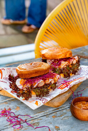 Zwei gefüllte Croissant-Burger auf Einwickelpapier, belegt mit Putenbrust, Salat und roten Sprossen.